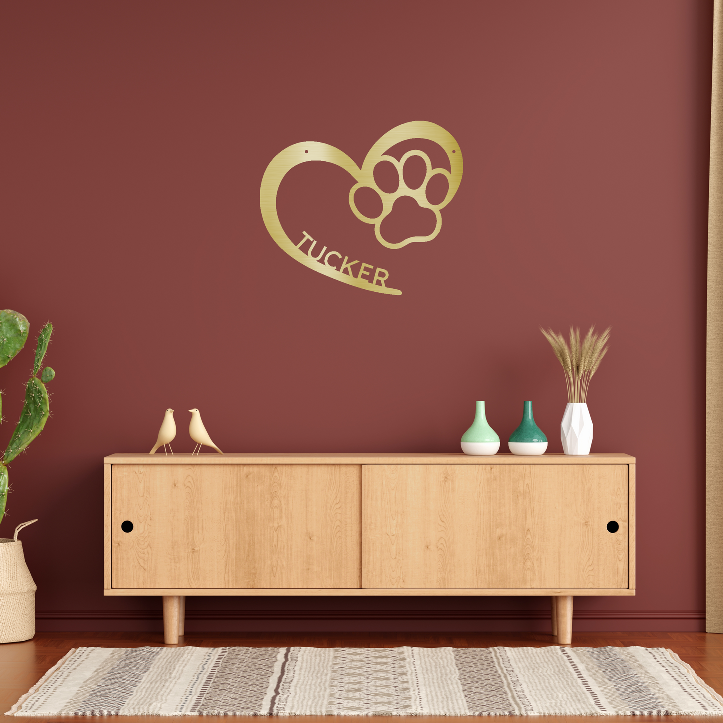 an open heart with a paw print in it, and personalized with a name, powder coat gold finish metal wall decor, hanging over a wooden cabinet on a rusty red accent wall | Home Accent Studio